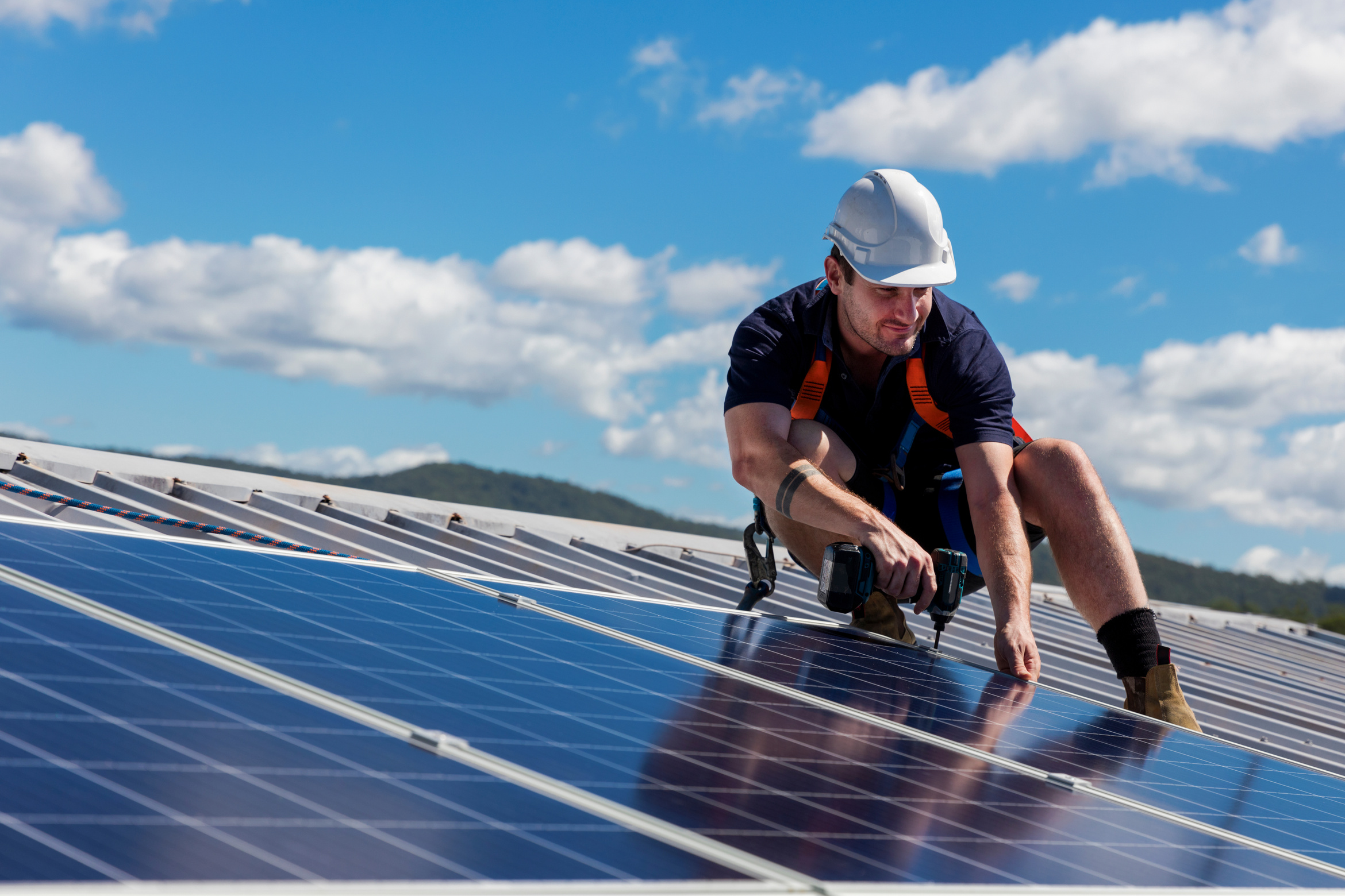 Solar Panel Technician with Drill Installing Solar Panels